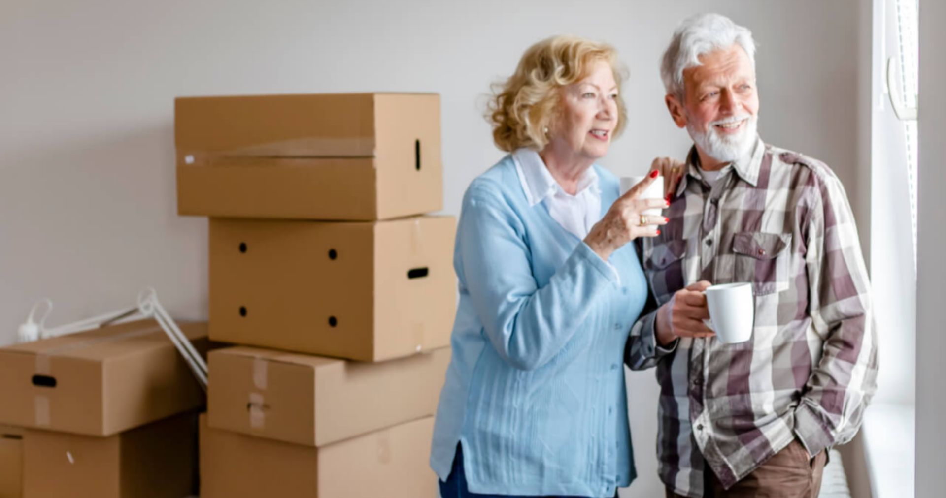 couple drinking coffee with moving boxes in background